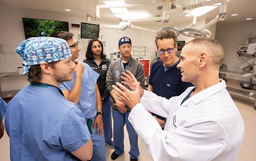 Residents in an operating room listening to a faculty member